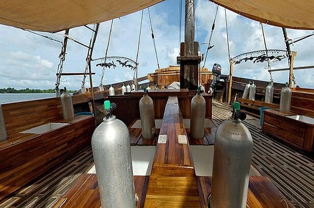 Dive deck of the Damai I liveaboard with scuba tanks set up in individual stations under a canvas awning