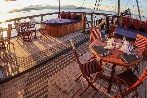 Outdoor dining table set at sunset on the Damai I's upper deck with island views