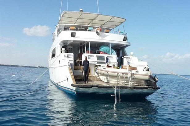 Crew member standing on the stern swim platform of the My Jessica with a tender boat alongside