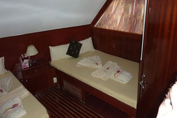 Twin cabin on the MY Jessica liveaboard with mahogany paneling and towels folded on the bed