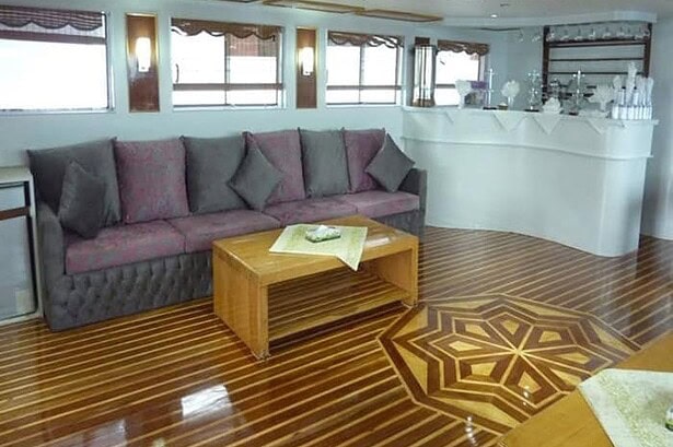 Saloon lounge on the MY Jessica liveaboard with a sofa, coffee table and drinks bar in the background