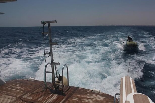 Wake behind the Blue Planet 1 with a tender dinghy trailing as the boat gets underway