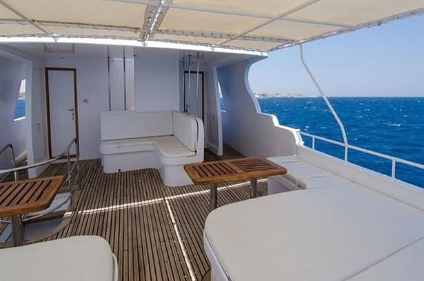 Shaded lounge area on the Blue Planet 1 with built-in bench seating and wooden tables