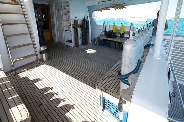 Dive deck on the Blue Planet 1 with tanks racked along the rail and gear ready for the next dive