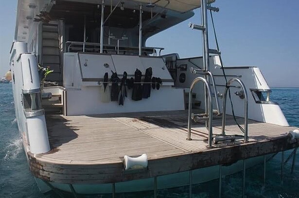 Stern dive platform on the Blue Planet 1 with wetsuits hung to dry and a ladder into the water