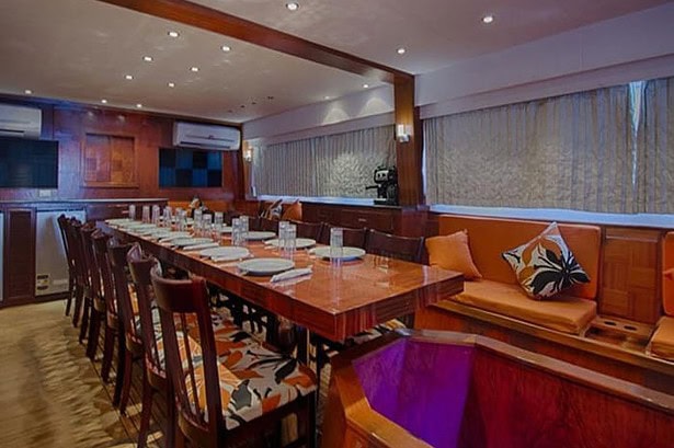 Long dining table and lounge seating in the Blue Planet 1's saloon, set for a group meal