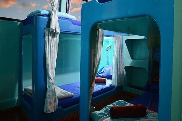 Curtained bunk beds in a twin cabin aboard the Similan Explorer, sunset light coming through the window