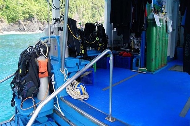 Individual scuba gear set up at stern stations on the Similan Explorer, limestone cliffs in the background