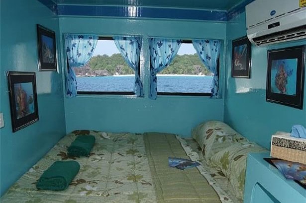 Double cabin on the Similan Explorer with a made-up bed, air conditioning and a window view of a tropical bay