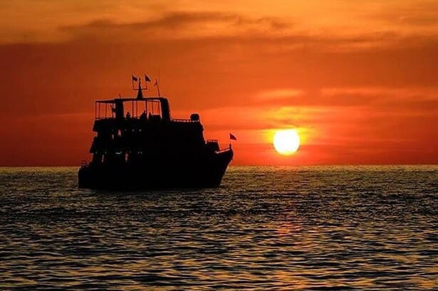 liveaboard dive boat silhouetted against an orange sunset at sea