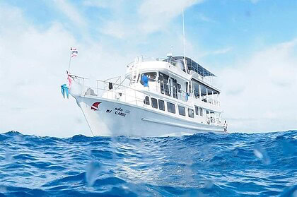 the liveaboard MV Camic cruising through choppy water, waves splashing in the foreground