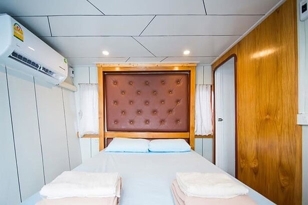 Double cabin on the MV Camic with a wall mounted air conditioner above the tufted headboard bed