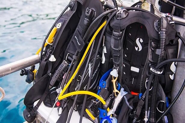 Scuba BCDs and regulators racked along the rail of the MV Camic between dives