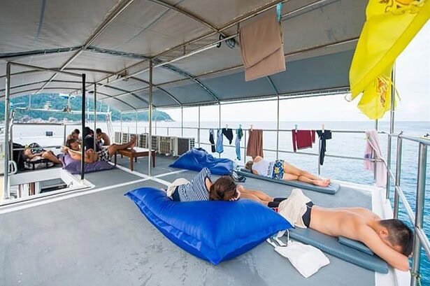 Guests relax on bean bag loungers on the MV Camic's shaded top deck with towels drying on a line