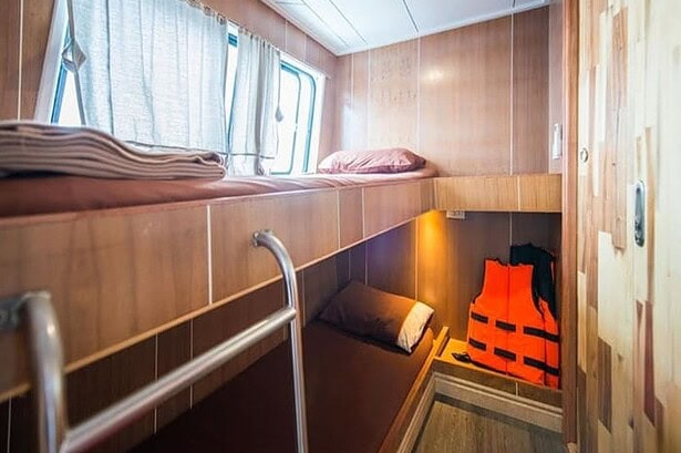 Wood panelled bunk cabin aboard the MV Camic with an orange life jacket stored below the bed