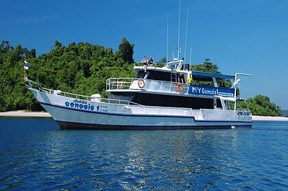 the liveaboard MY Genesis 1 anchored beside a forested island in Thailand