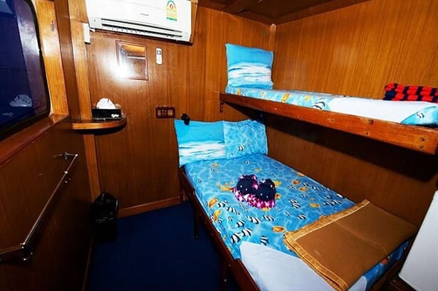Twin bunk cabin aboard the MV Marco Polo with reef print linens and a wall mounted air conditioner