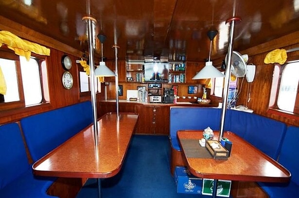 Wood paneled lounge aboard the MV Marco Polo with a TV, bookshelf and dining tables