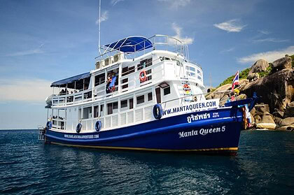 Manta Queen 5 liveaboard boat at anchor near a forested island in Thailand
