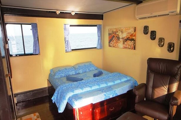 The master cabin aboard the Oktavia with a double bed and tribal masks on the wall
