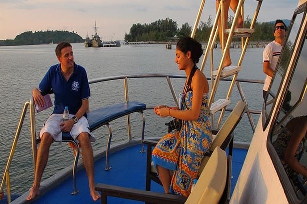 Guests relaxing on the Oktavia liveaboard's aft deck at sunset with the flybridge ladder in view