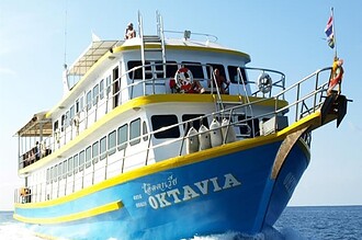 Oktavia liveaboard boat cruising with divers on deck and dive tanks stowed at the bow