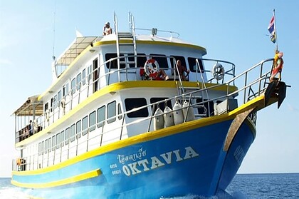 Oktavia liveaboard boat cruising with divers on deck and dive tanks stowed at the bow