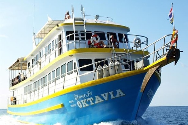 Oktavia liveaboard boat cruising with divers on deck and dive tanks stowed at the bow