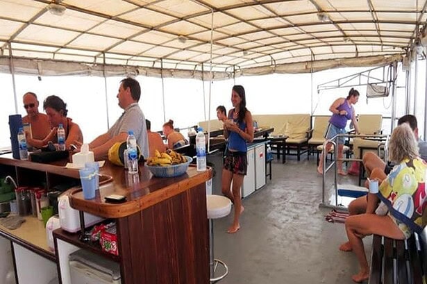 Guests relax in the covered communal lounge aboard the Oktavia with snacks laid out