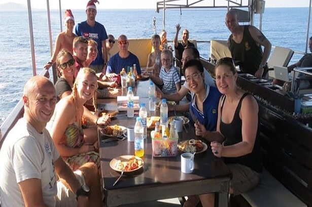 Guests sharing a festive holiday meal at the long dining table on the Oktavia's deck