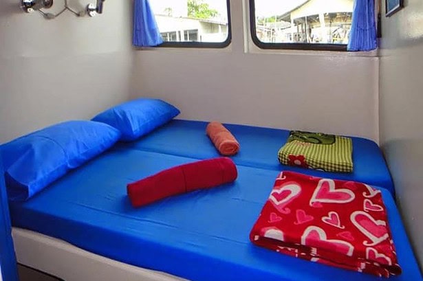 A double cabin aboard the Oktavia with blue bedding, rolled towels and a heart-print blanket