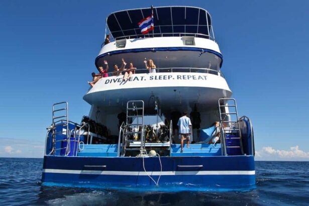 Guests wave from Manta Queen III's upper deck above the Dive Eat Sleep Repeat sign on the stern