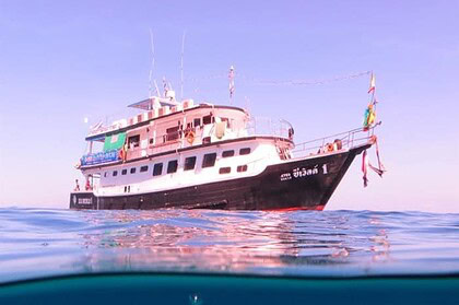 The Sea World 1 liveaboard at dusk with its bow reflected in still water