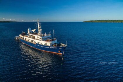 Solitude One liveaboard anchored off a tropical Micronesia coastline, aerial view