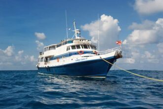 Caribbean Explorer II liveaboard dive boat anchored in calm water under a partly cloudy sky
