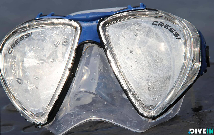 Cressi Penta+ Mask Low Volume Design Wet Cressi Penta+ mask resting on a beach, showing its clear low-volume skirt and blue frame