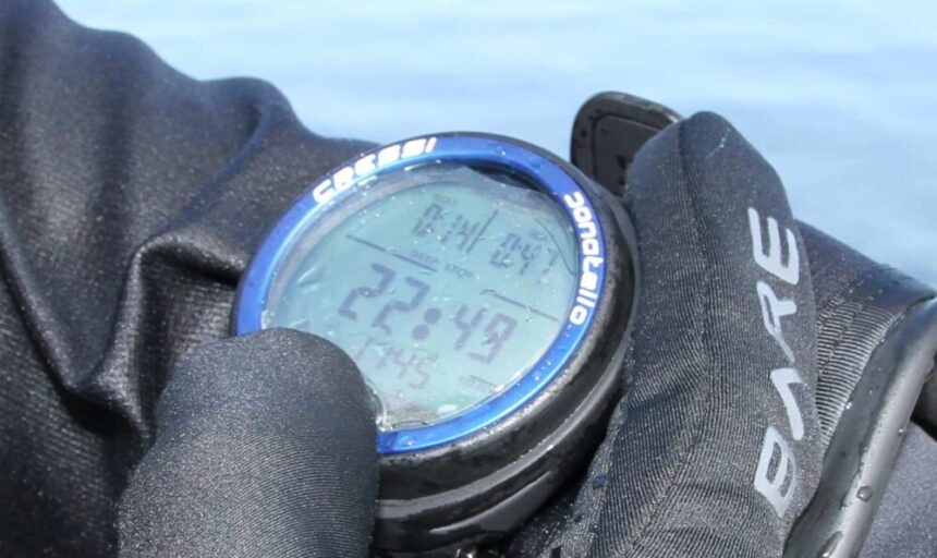 Cressi Donatello Dive Computer In Hand DIVEIN tester holding the Cressi Donatello dive computer in wet gloves, reading the dive time on its display
