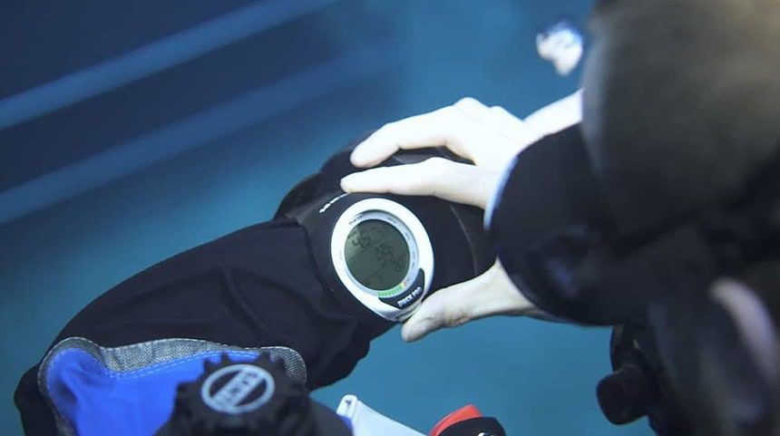 Mares Puck Pro Checked Underwater Our tester checking the Mares Puck Pro strapped to a fellow diver's forearm underwater