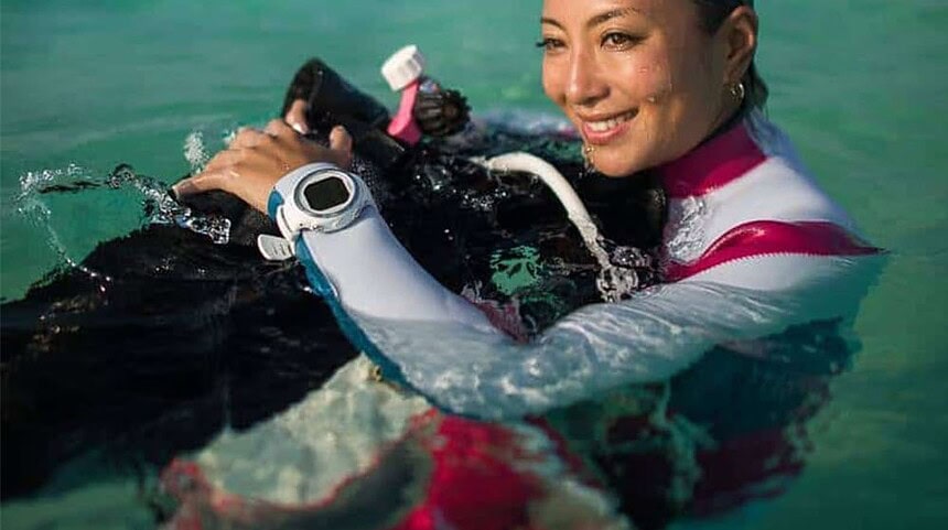 Diver At The Surface Wearing A Dive Computer Diver in a pink and white wetsuit smiling at the surface with a white dive computer on her wrist