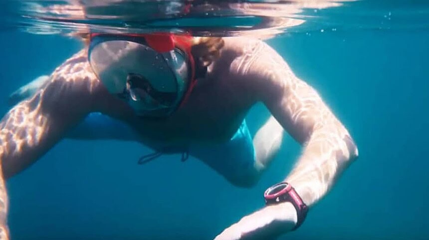Snorkeler wearing a Cressi Neon dive computer on the wrist while swimming near the surface