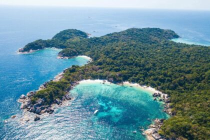 Aerial view of a forested island with a turquoise lagoon and reef off Myanmar's coast
