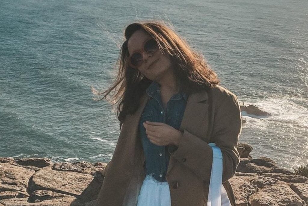 Anastasia, DIVEIN staff writer, standing on a coastal cliff by the sea