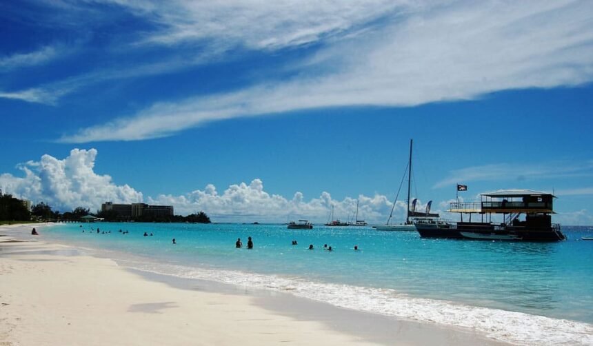 White sand beach at Carlisle Bay, Barbados, with turquoise water, swimmers and boats moored offshore