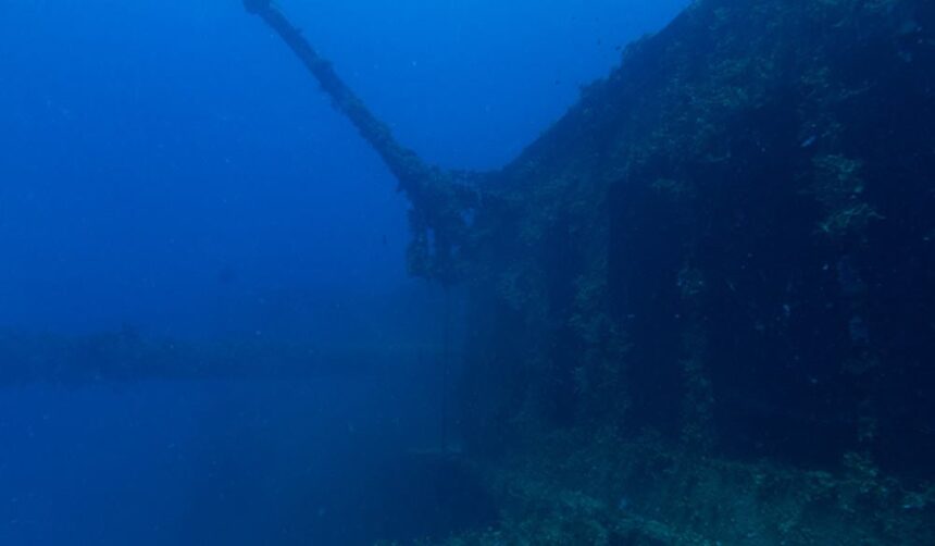 Coral-covered structure angling up through deep blue water at Barracuda Junction, Barbados