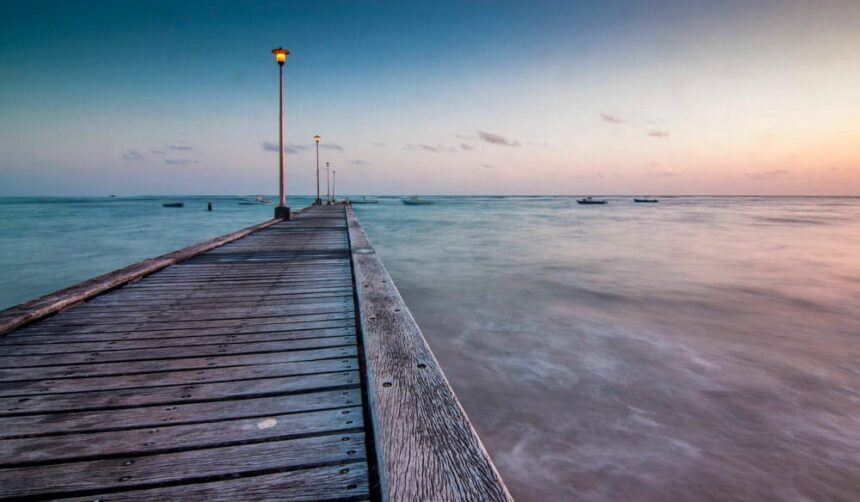Wooden jetty stretching into calm water at dusk at Consett Bay on the Atlantic coast of Barbados
