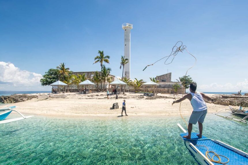 Boat crew throwing a mooring line toward the lighthouse islet of Capitancillo Island