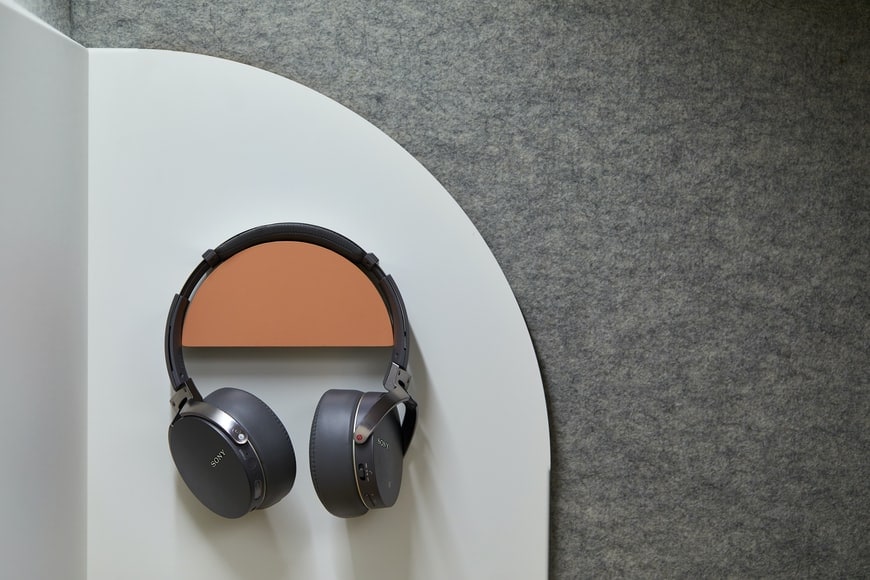 Black Sony over ear headphones hang against a felt textured wall
