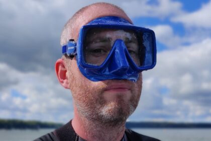 DIVEIN tester wearing the blue Cressi SF1 mask with lake and cloudy sky behind him