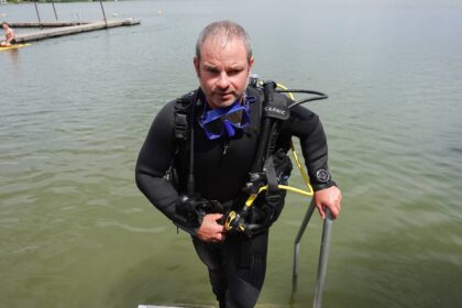 Our reviewer climbing out of the lake in the BARE Reactive 7mm wetsuit with full scuba kit on