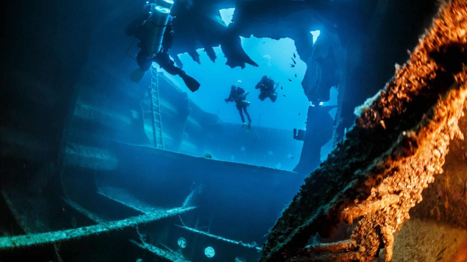 Divers exploring the broken hull of the El Aguila wreck in Roatan
